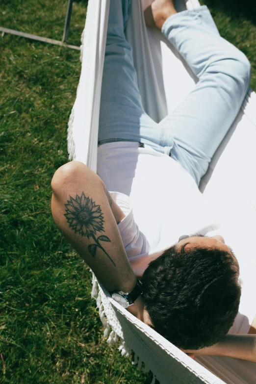 man laying in a hammock with his arm tattoo