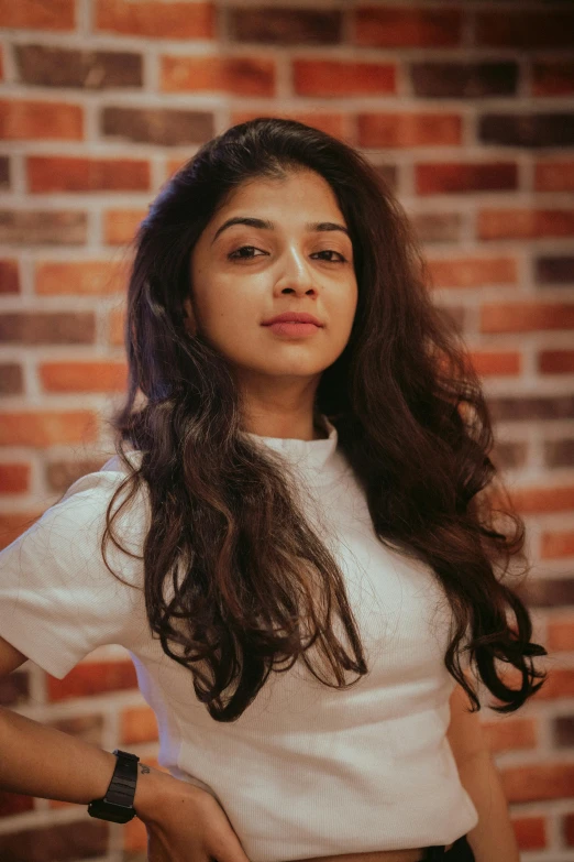 a young woman standing in front of a brick wall