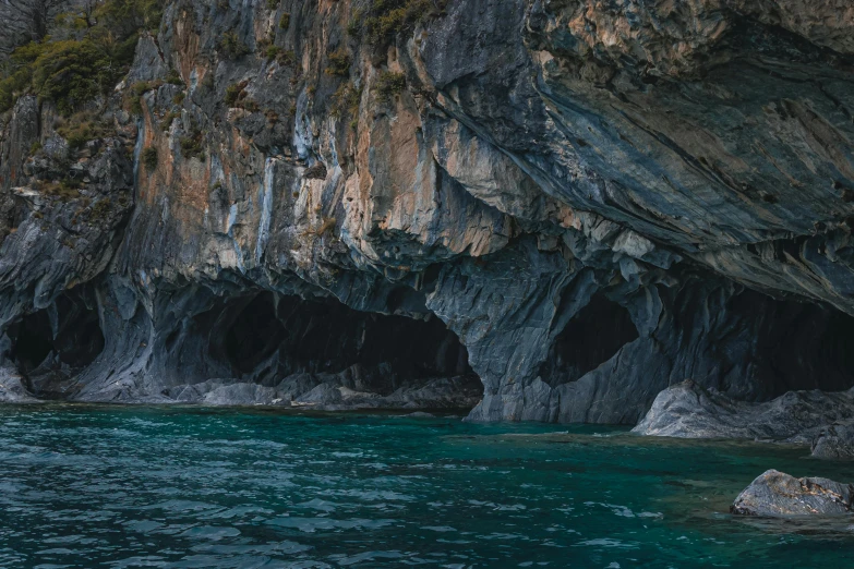 some people floating in a boat near a cave