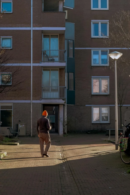 a person wearing an orange hat and backpack walking in front of a building