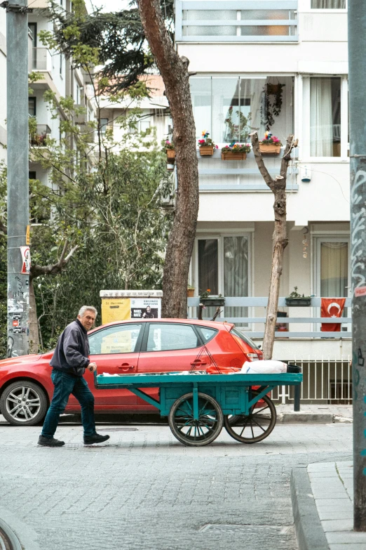 a man walks down a street past a red car