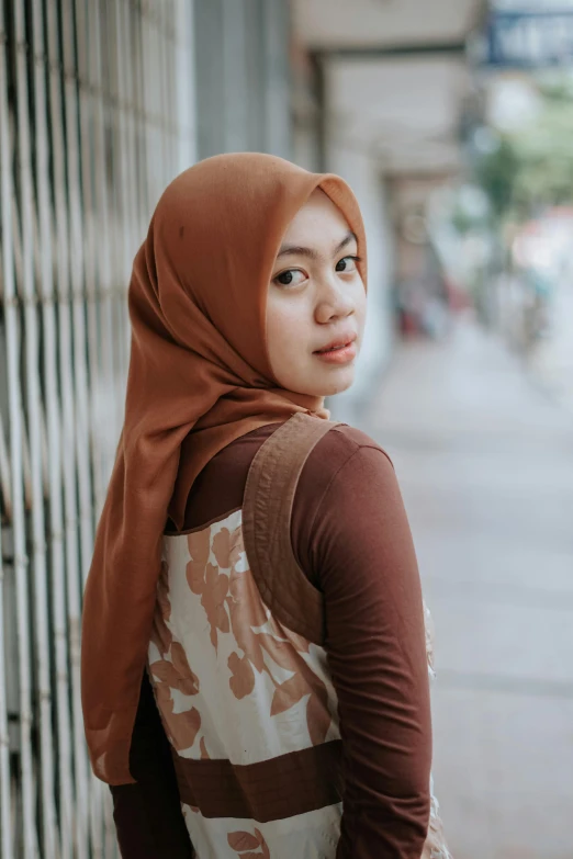 a woman standing on the sidewalk wearing a head covering