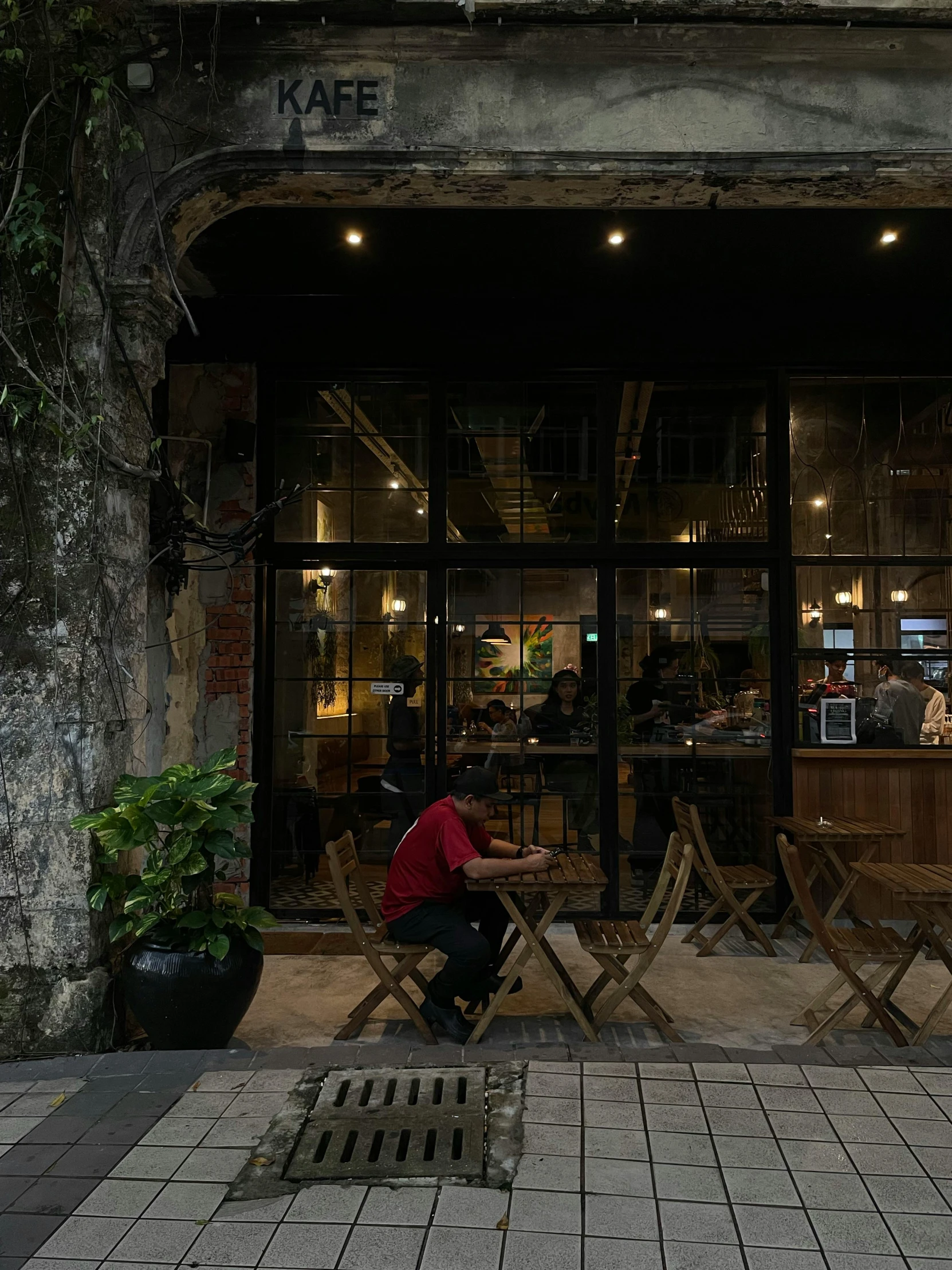 the man is sitting at the table in front of the shop