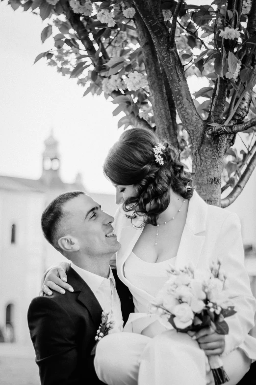 a bride and groom kissing in front of a tree