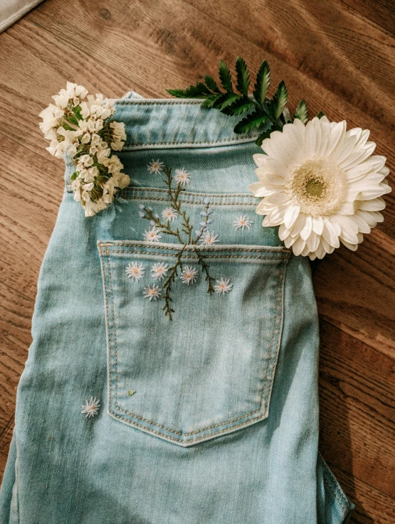 a flower and some leaves placed in a pair of blue jeans