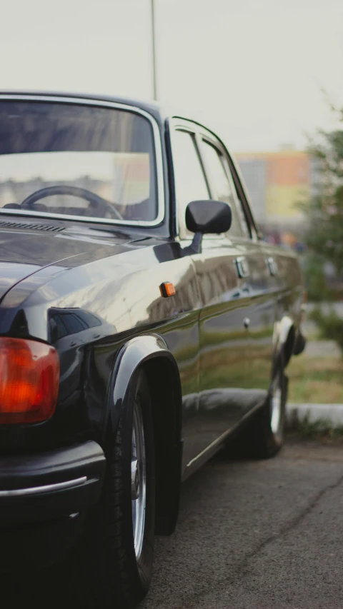 an old, shiny mercedes sits parked on the street