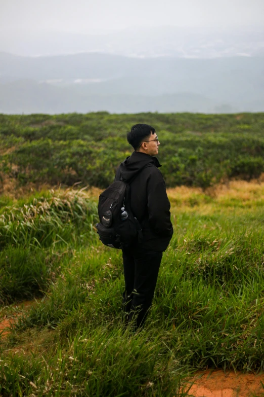 a man standing in tall green grass on a mountain