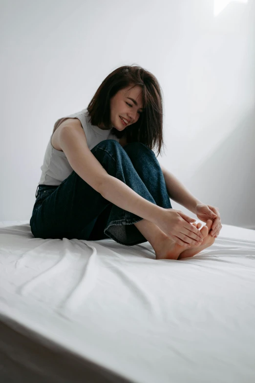 a young woman sitting on the bed with her hands near her face