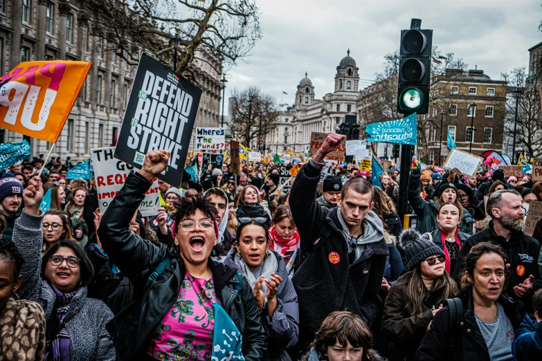 people protesting in front of a group of buildings and one person is holding up a traffic light