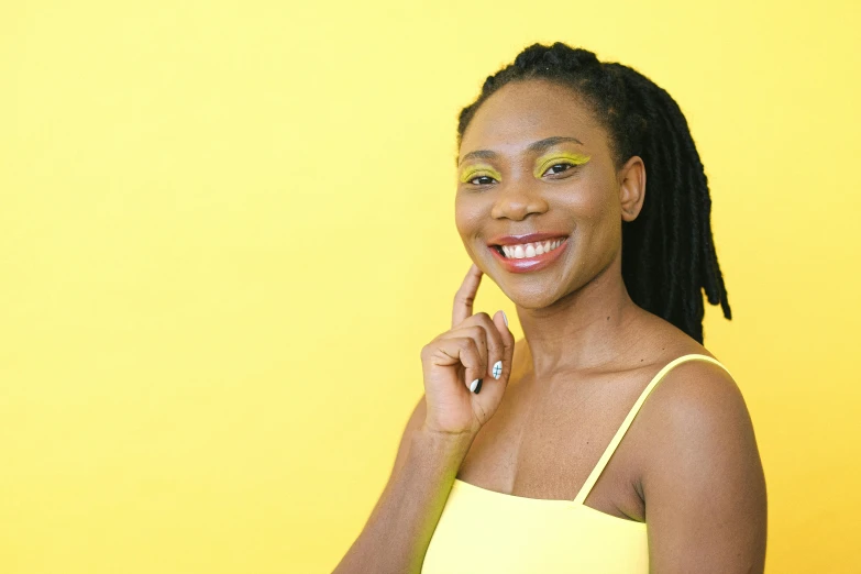 smiling woman in front of yellow background, with natural makeup