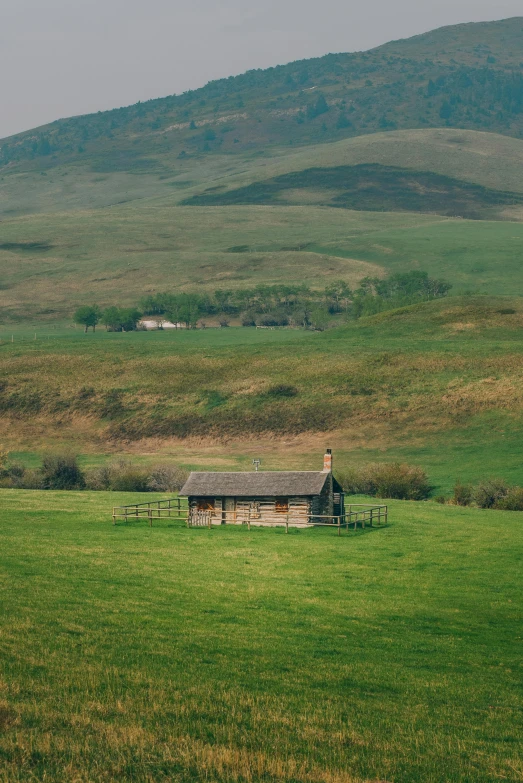 an old house sitting in the middle of a lush green field