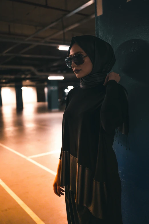 a woman in a black top and sunglasses stands near a building