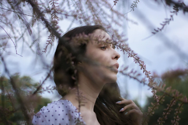 woman with hair blowing in the wind in front of trees