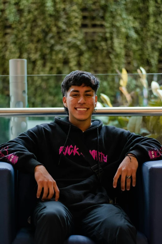 young man smiling while wearing headphones while sitting on a chair