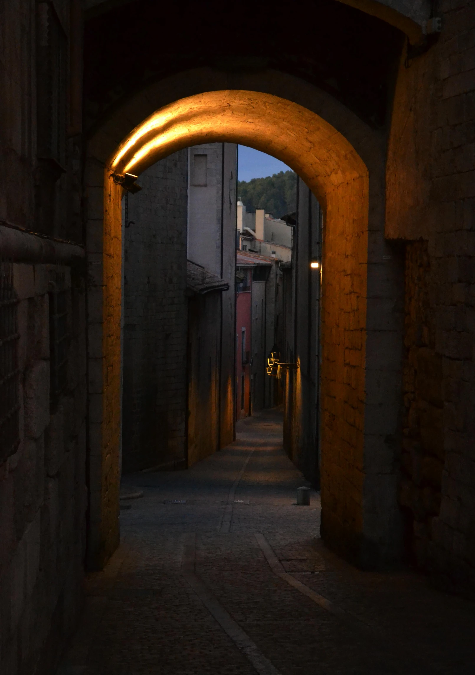 a dark alley with an archway leading to another building