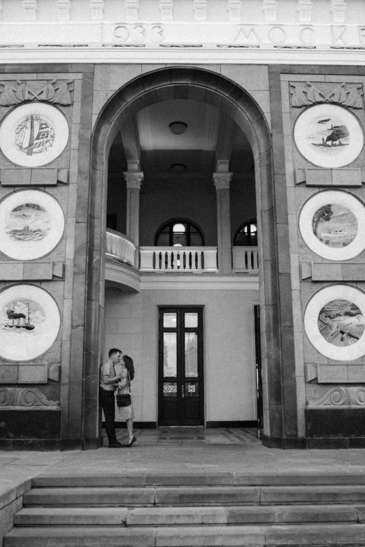 two people standing in front of a building