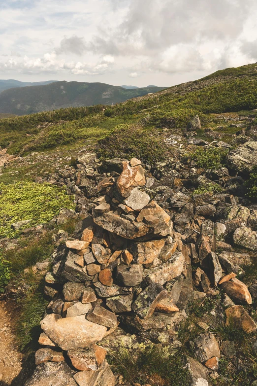 a grassy hill covered in rocks on a cloudy day