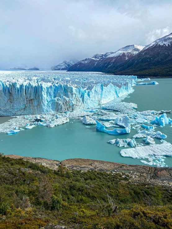 an icy mountain with large blue pieces on the lake