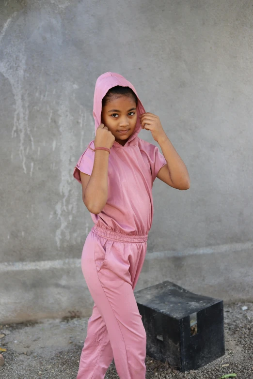 a child in pink wearing a hoodie and holding a suitcase