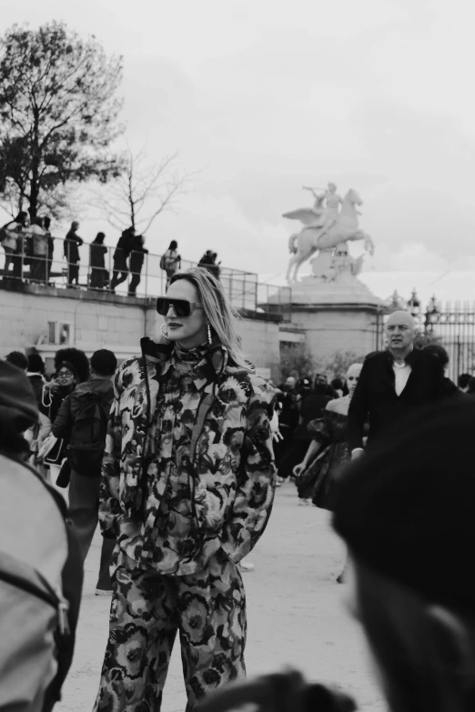 a woman with sunglasses, standing in front of a crowd