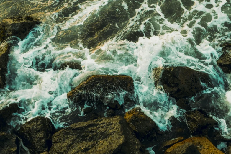 rocks with waves crashing up on them near the shore