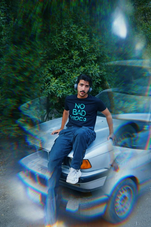 a man sitting on the hood of a silver car