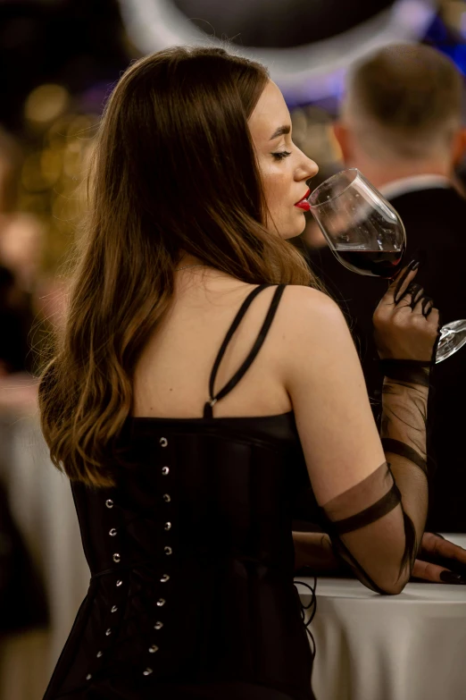 a beautiful woman wearing a black dress drinking wine
