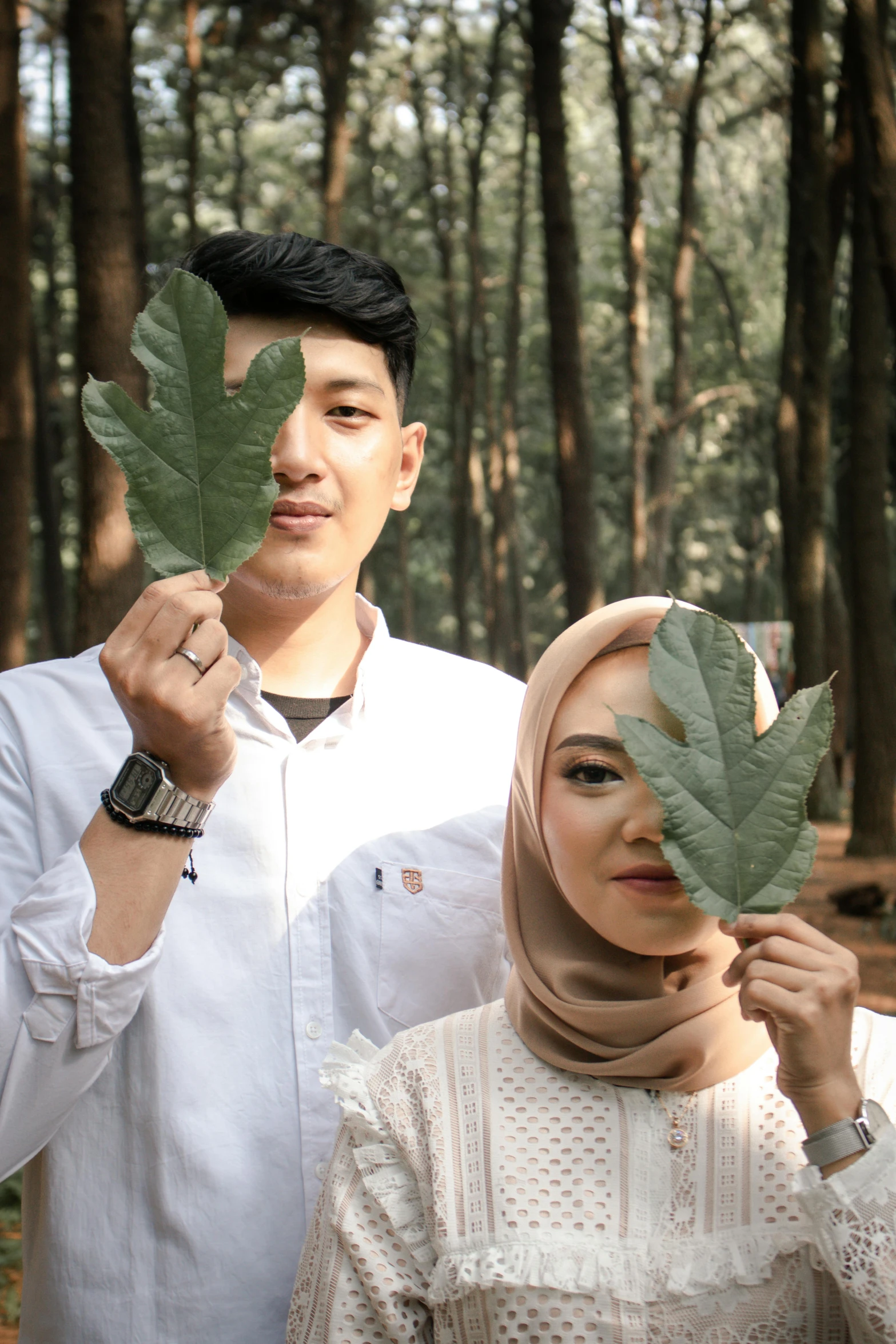 a man and woman are holding leaves in their hands