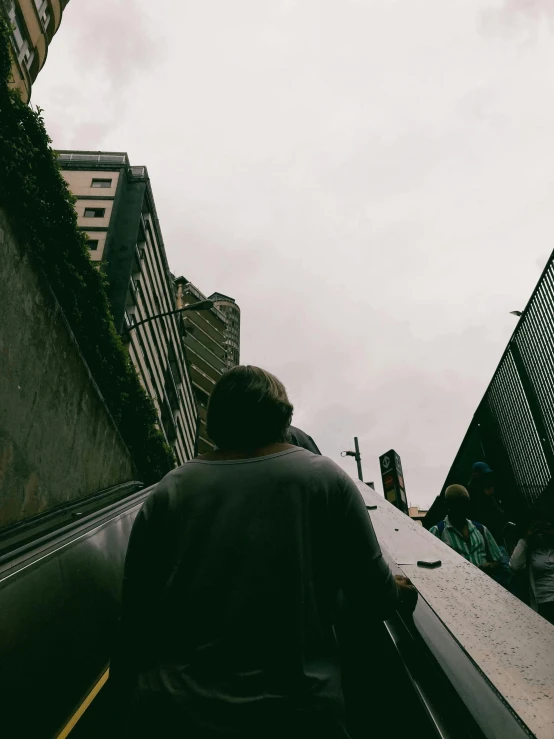 man moving down an escalator into another platform