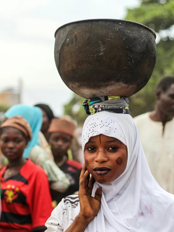 a woman with a bucket on her head on a cell phone