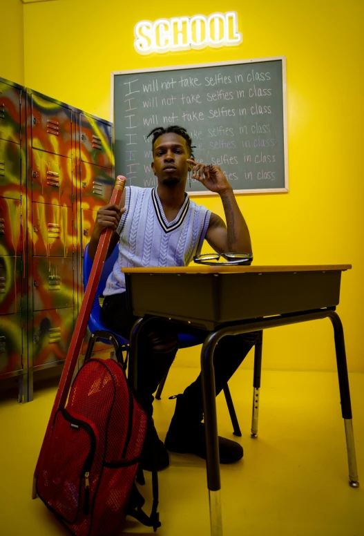 a young man is sitting in front of a school desk