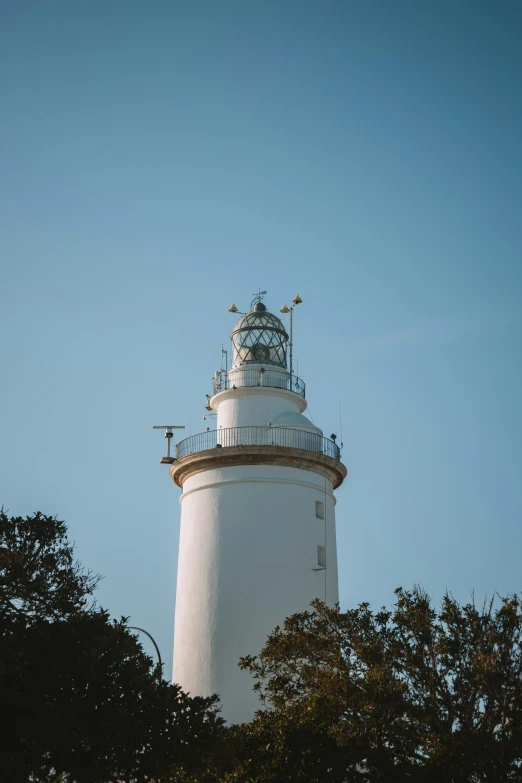 a white light house standing over trees