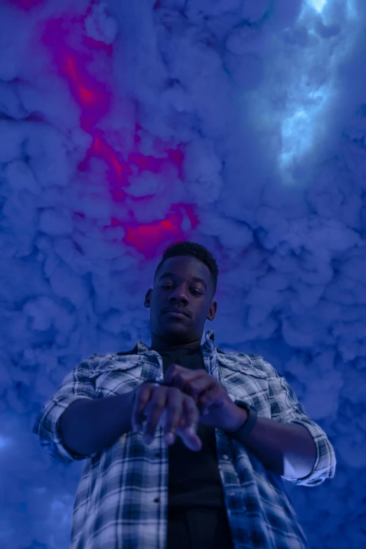 a man standing in front of clouds and blue lights