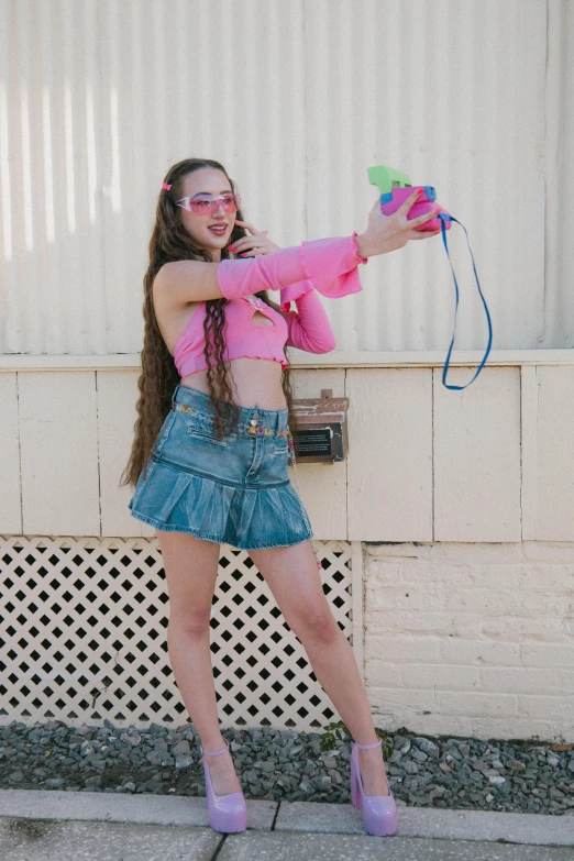 girl wearing blue jean shorts and pink jacket holding a toy