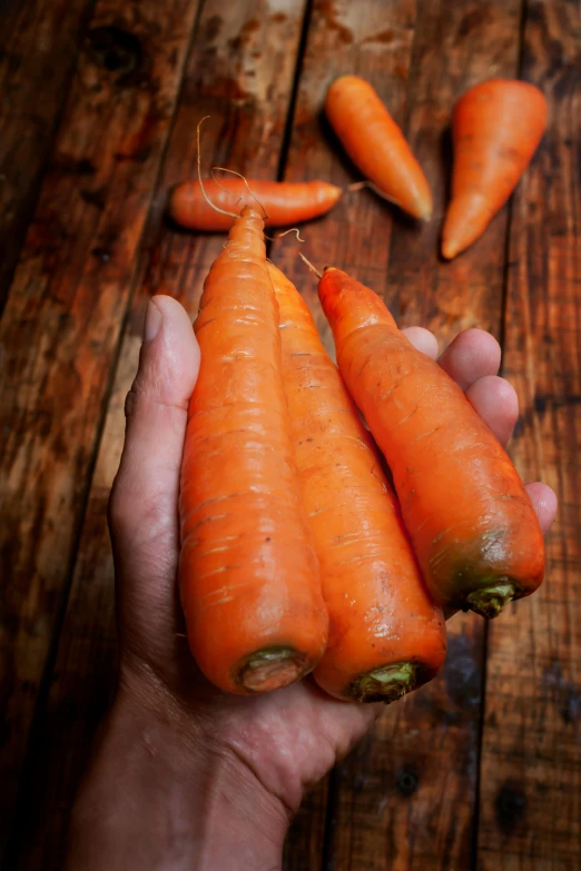 a person holding three carrots and one whole carrot