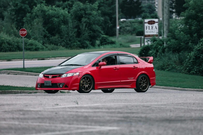 a red car sitting in the middle of a parking lot