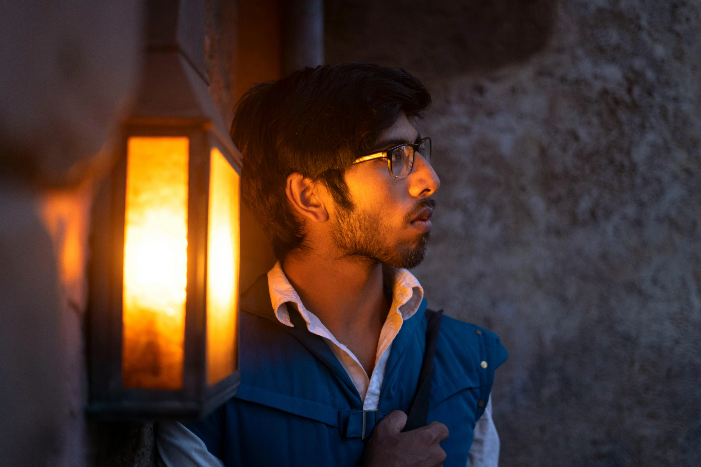 man standing beside a lamp in the city at night