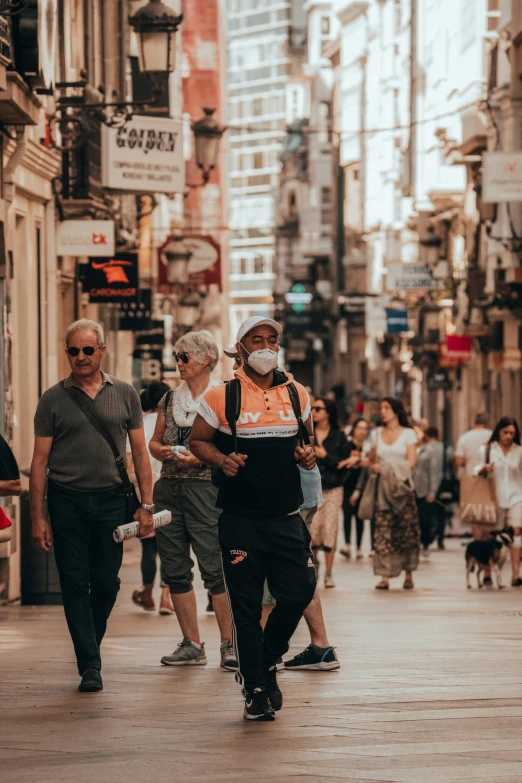 a man walking in the middle of a street wearing a safety vest and an orange vest