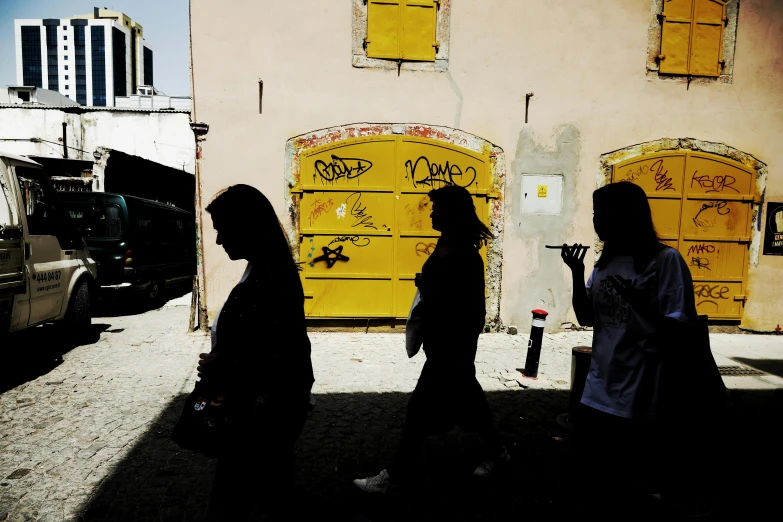 several people walking in silhouette next to some graffiti