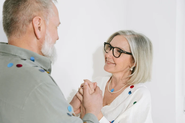 the older man has his hands together and a woman in the foreground is holding him