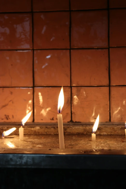 five lit candles sitting on a counter in front of a brick wall