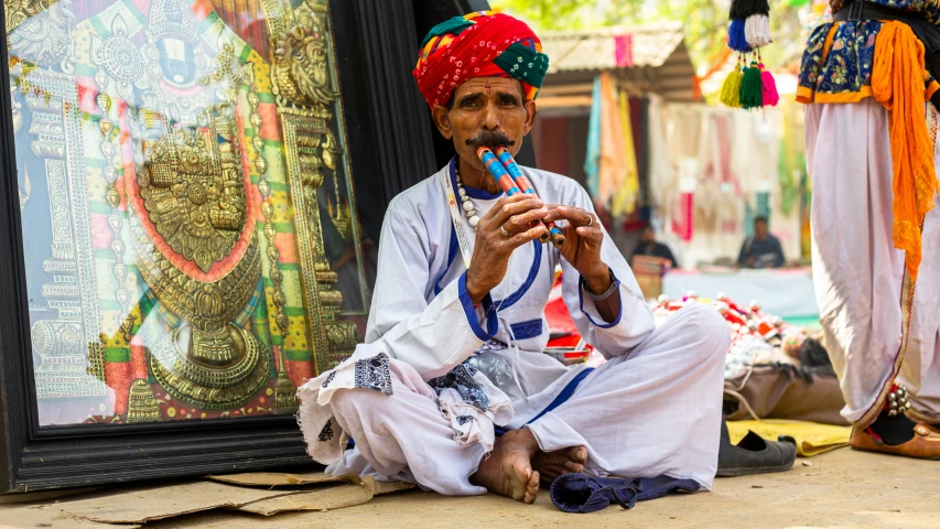 the man in white clothing is playing a flute