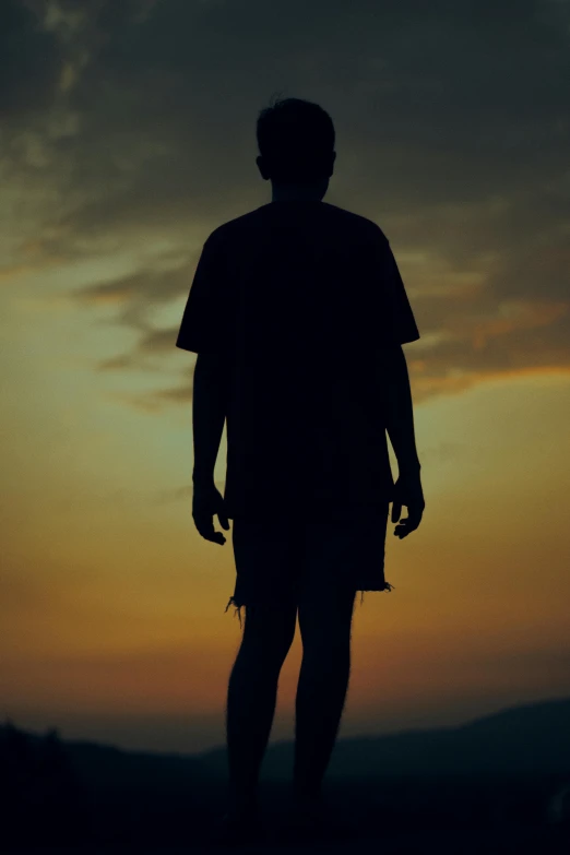 a person silhouetted against a dusk sky while holding an umbrella