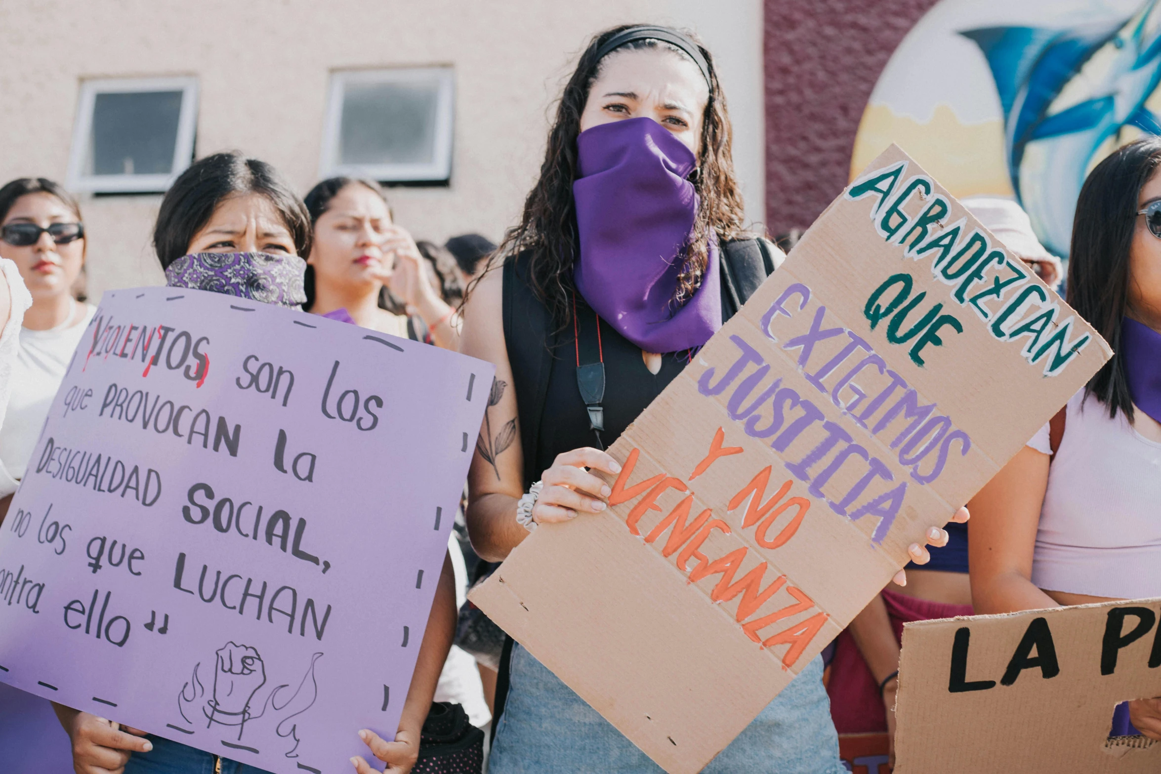 a group of women holding placares, wearing masks and standing in the street