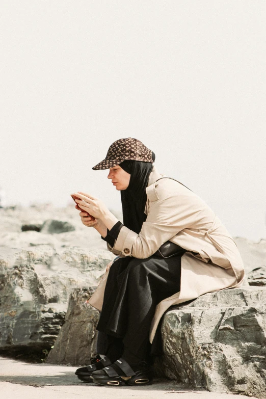 a person with a hat sitting on a rock