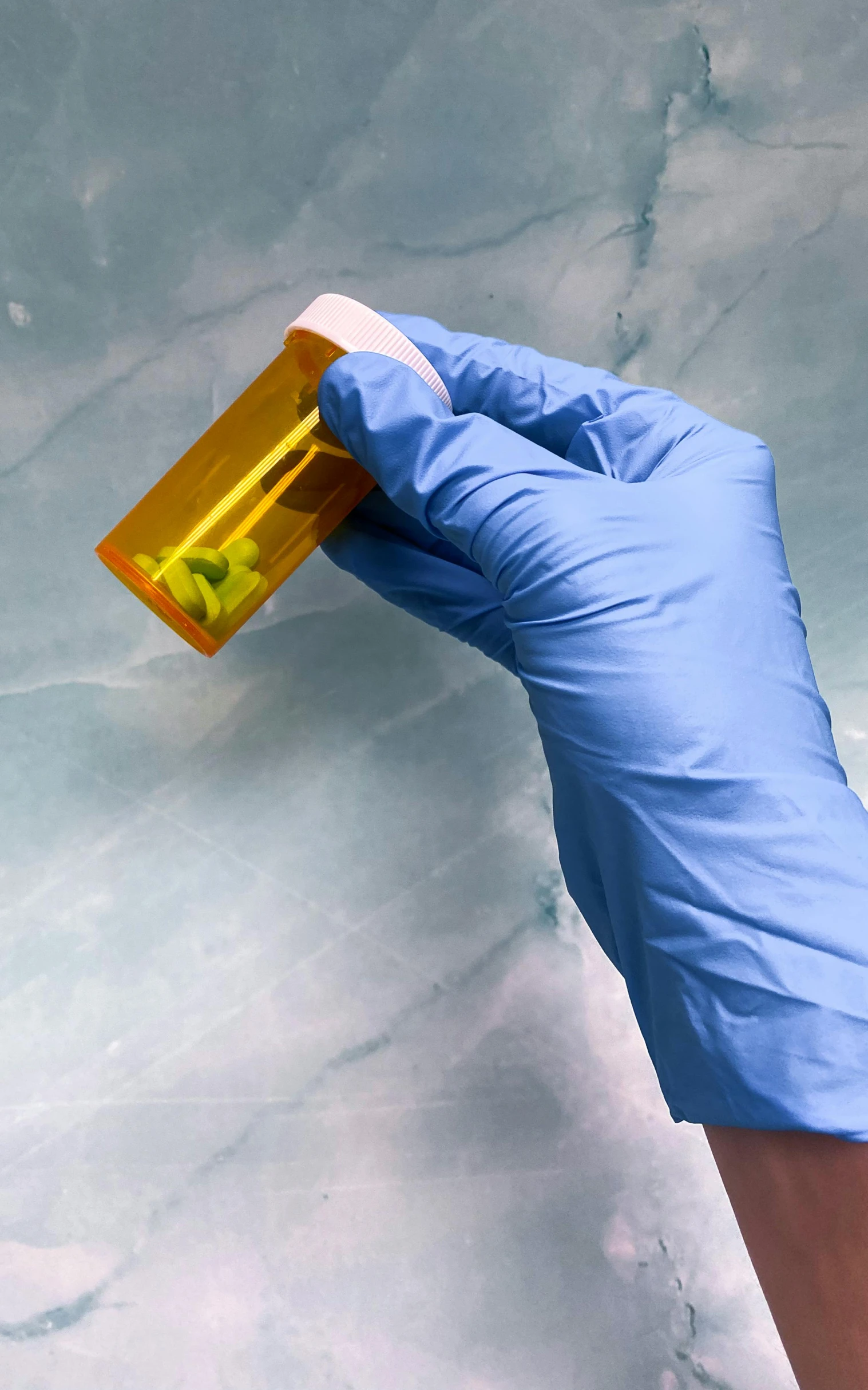 a gloved hand with blue gloves is holding a yellow container