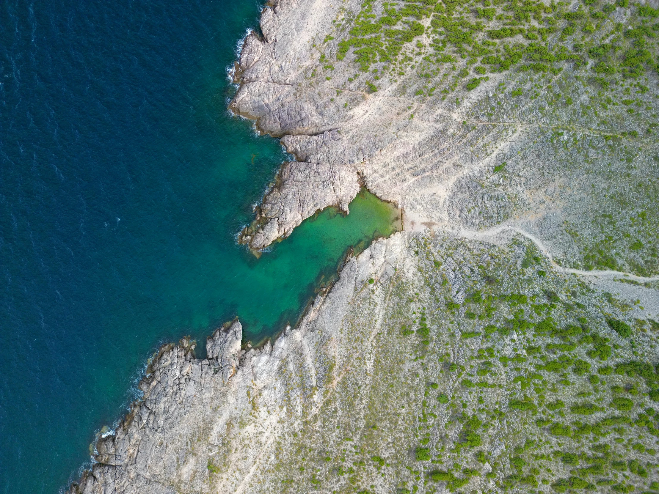 an aerial view of rocks and water in the middle of a lake