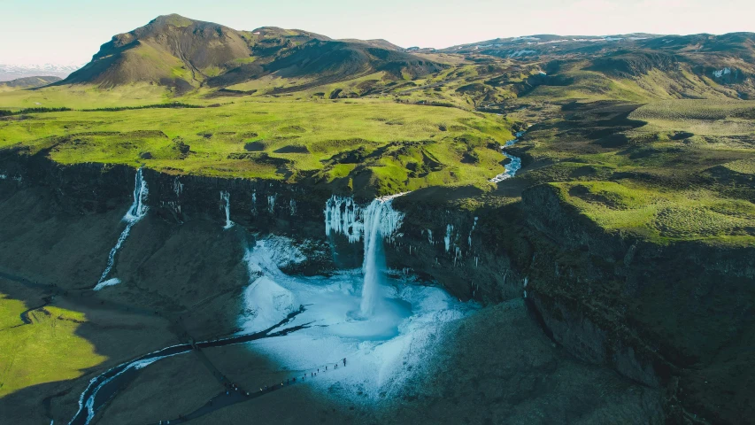 an aerial view of a waterfall near mountains