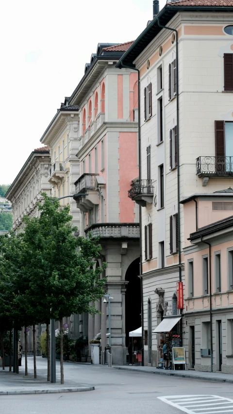 a large multistory building with shops and pedestrians on the side