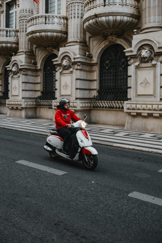 a person in red shirt on motorcycle next to building